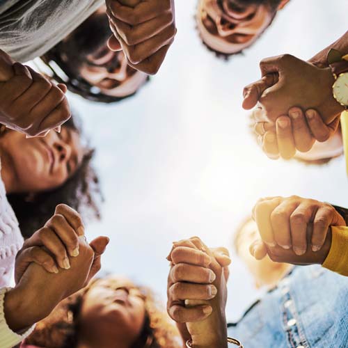 Group of people holding hands in a circle during Empower, a faith-based training session