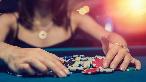 A woman at power table gambling with pile of chips demonstrating a behavioral health disorder.